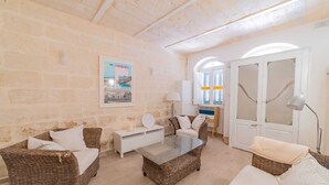 A cozy living room with wicker furniture, a glass coffee table, and a white sofa. - Central Valletta Townhouse (Valletta)