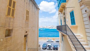 A narrow street leading to a waterfront with buildings on either side. - Central Valletta Townhouse (Valletta)