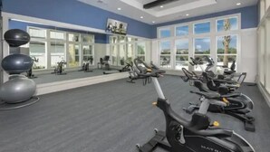 Ein Fitnessstudio mit Cardiogeräten, Gewichtstrainern und großen Fenstern mit Blick ins Freie.