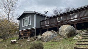 A two-story cabin with a balcony, large rocks, and a satellite dish. - Sunset views in the foothills (Rough and Ready)
