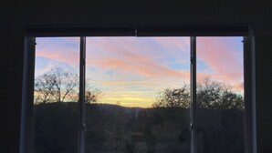 A window with a view of a sunset over a forested landscape. - Sunset views in the foothills (Rough and Ready)