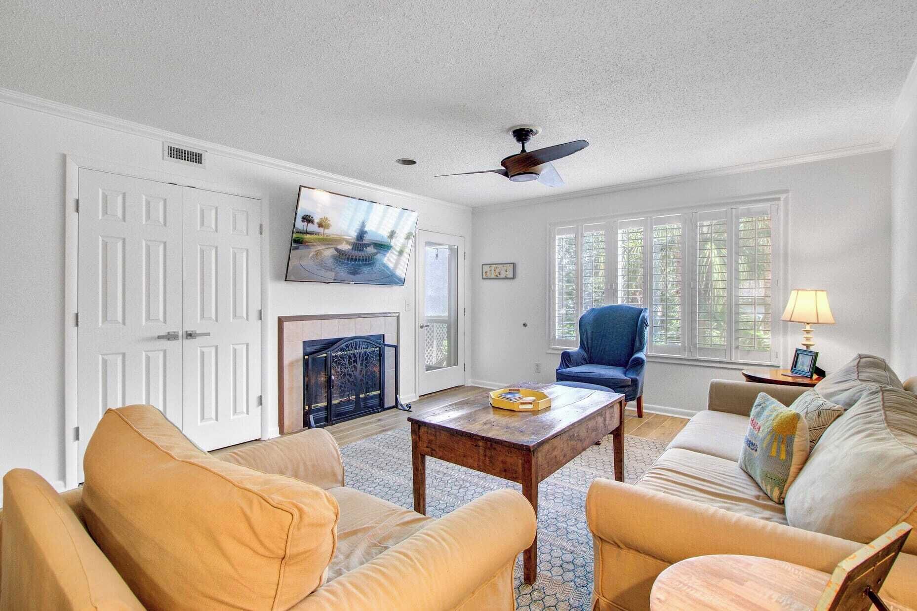 A living room with a fireplace, a television, and a ceiling fan.
