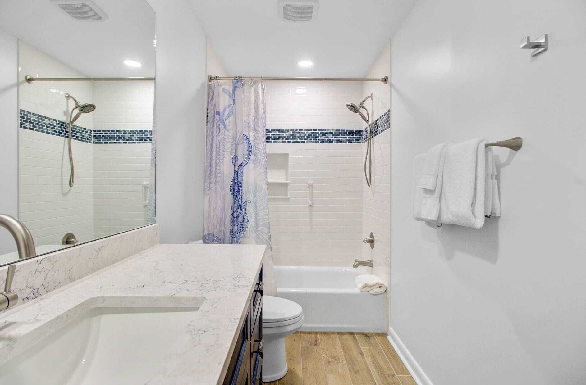 Un baño con lavamanos blanco, espejo, inodoro, bañera y ducha.