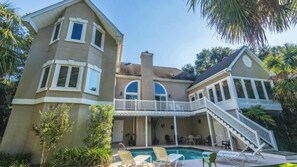 Une maison à deux étages dotée d’un patio couvert, d’une piscine et de mobilier d’extérieur.