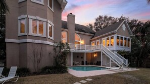 Une maison à deux étages dotée d’une piscine, d’un patio couvert et d’un escalier menant à un balcon.