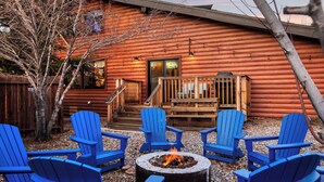 A log cabin with a deck, outdoor seating, and a fire pit.