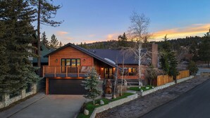 A log cabin with a garage, a deck, and a stone wall.
