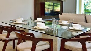 A modern dining area with a glass table, wooden chairs, and a sofa.