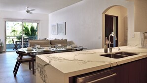 A modern kitchen with a marble countertop, a built-in sink, and a ceiling fan.