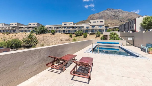 Zona de piscina en la azotea con sillones, una piscina y vistas a la montaña.