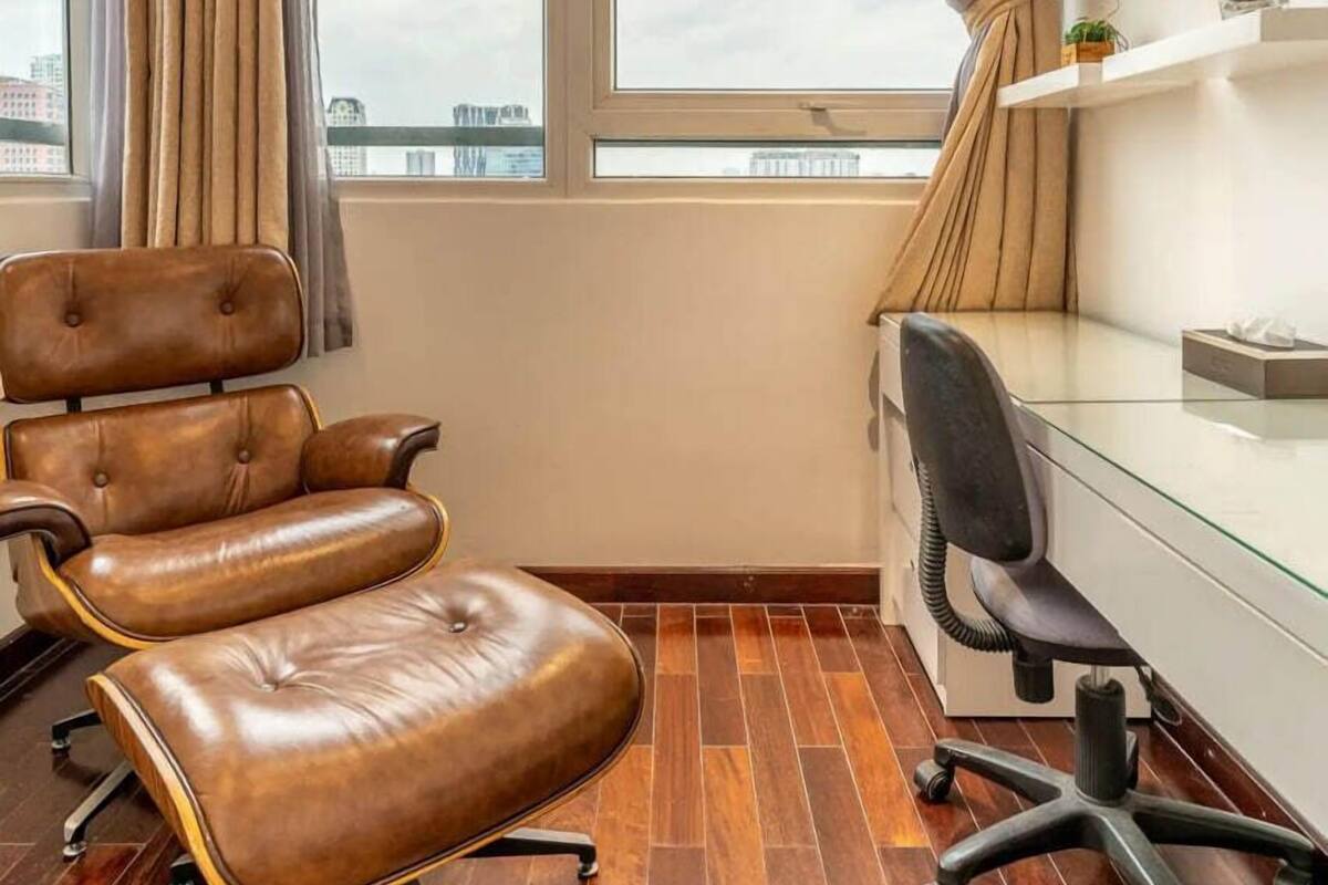 A modern office space with leather chairs, a glass desk, and a decorative chandelier.