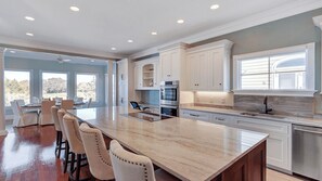 A modern kitchen with a large island, white cabinetry, and stainless steel appliances.