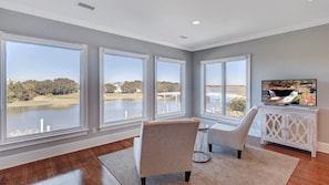 A spacious room with large windows, a television, and a seating area.