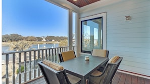 A balcony with a table and chairs, a view of a body of water, and a building in the background. - 20 Morgan Place Drive by Avantstay Waterfront Home w/ Private Dock (Isle of Palms)