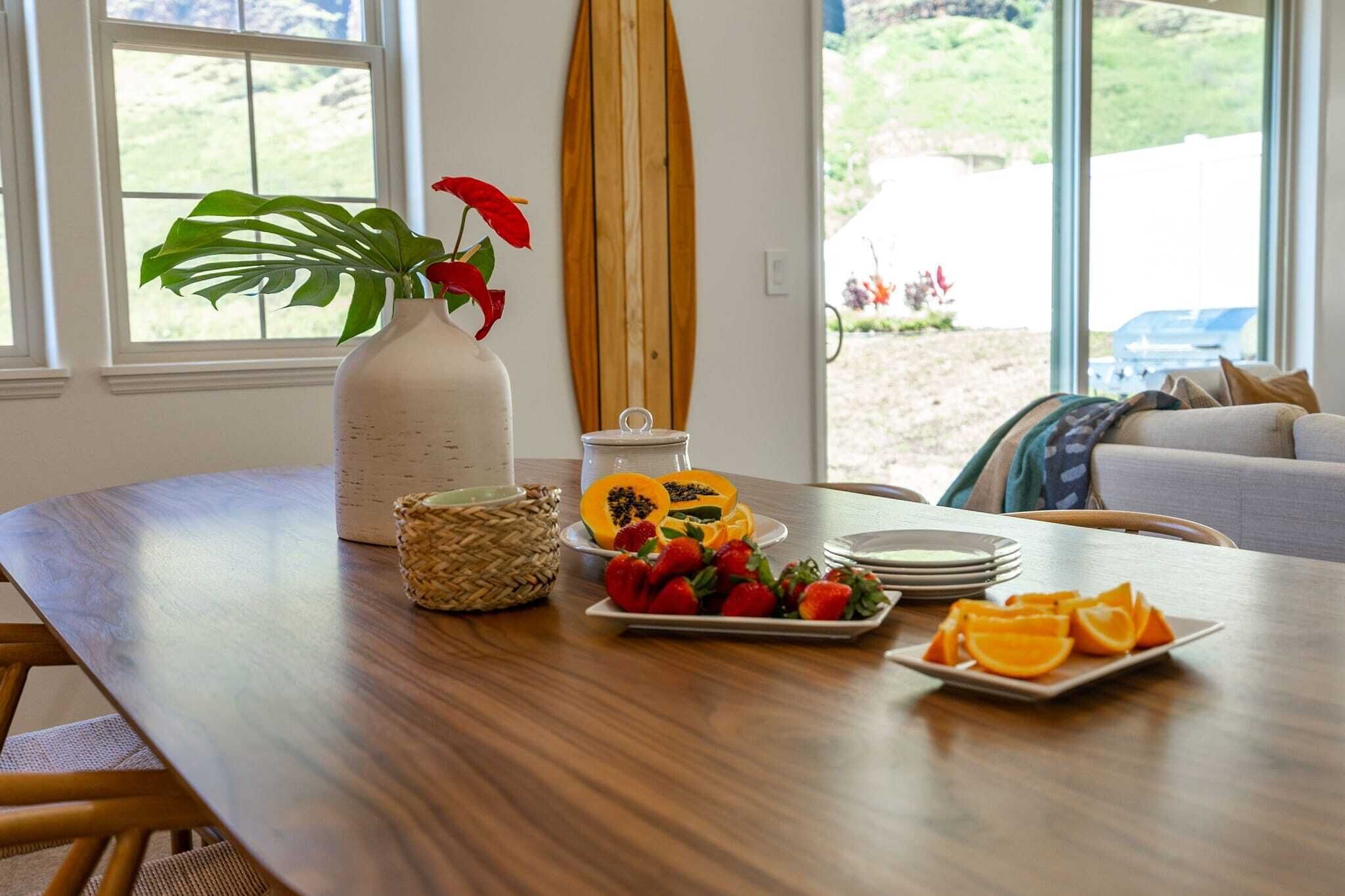 Een houten eettafel met een witte vaas, een gevlochten mand en schalen met fruit.