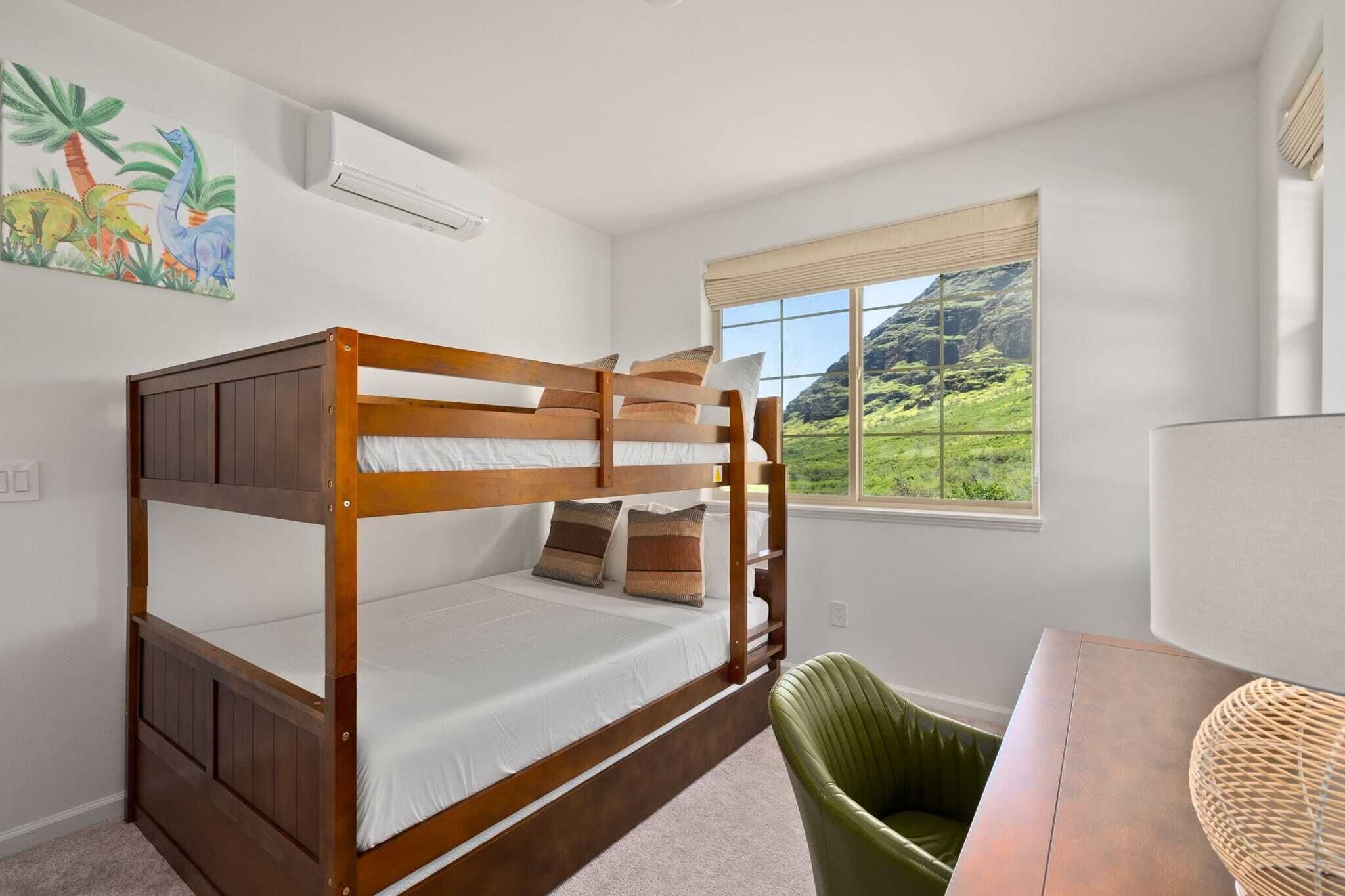 A bunk bed room with a view of a green landscape through a window.