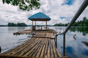 Un radeau en bambou doté d’un toit de chaume et d’un espace pour s’asseoir, sur un lac paisible.