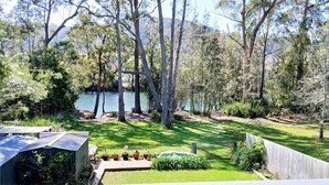A backyard with a pond, surrounded by trees and a wooden fence.