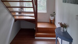A wooden staircase leading to a landing with a small table and potted plant.