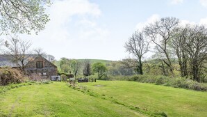 A rural landscape with a stone building, a grassy field, and trees. - The Hawthorns (South Molton)