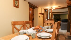 A dining table set with plates, cups, and a teapot, surrounded by wooden chairs. - The Hawthorns (South Molton)