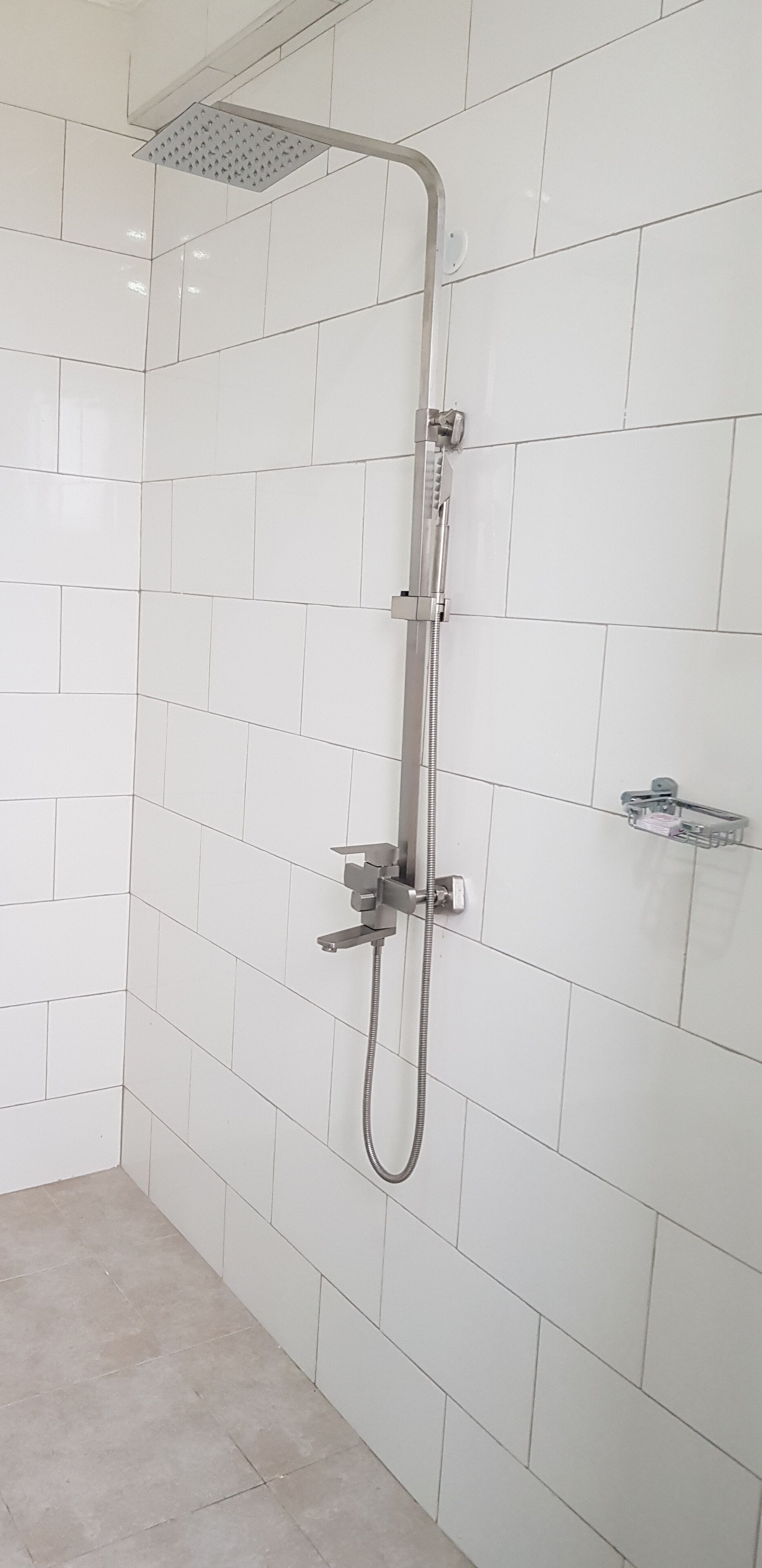 A shower with a handheld showerhead and a fixed showerhead mounted on the wall.