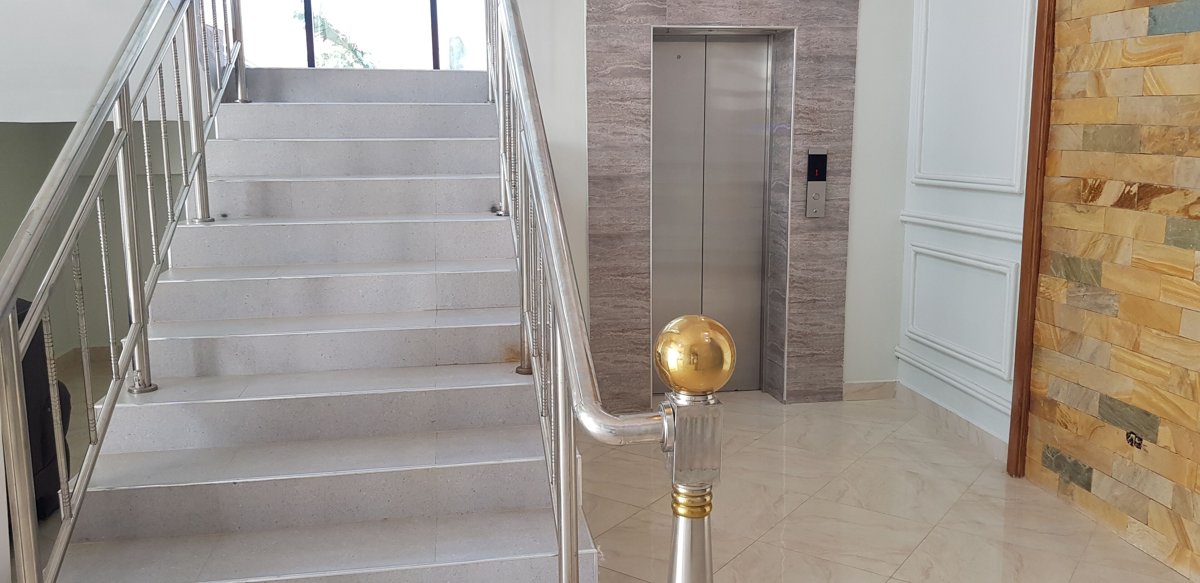 A staircase with a handrail and a golden spherical object at the bottom.