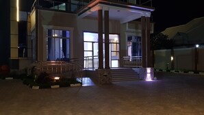 Un edificio moderno con entrada cubierta, escalones que conducen a un porche y un sendero bien iluminado.