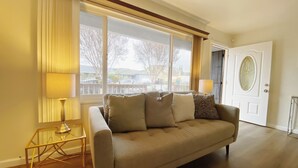 A living room with a beige sofa, two lamps, a glass coffee table, and a door with a decorative glass panel. - Home in Union City
 (Union City)