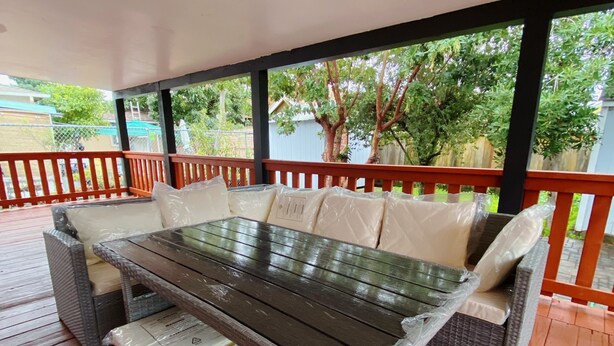 A covered outdoor seating area with a glass-top table and wicker furniture. - Home in Union City
 (Union City)