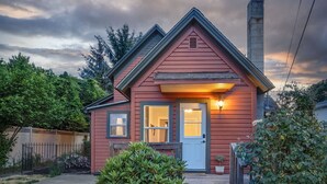 Una casa roja con puerta blanca, un pequeño porche y una luz en la fachada.