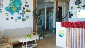 A reception area with a map, a clock, a bench, and a table with a plant. - Happy Island Inn (Virac)