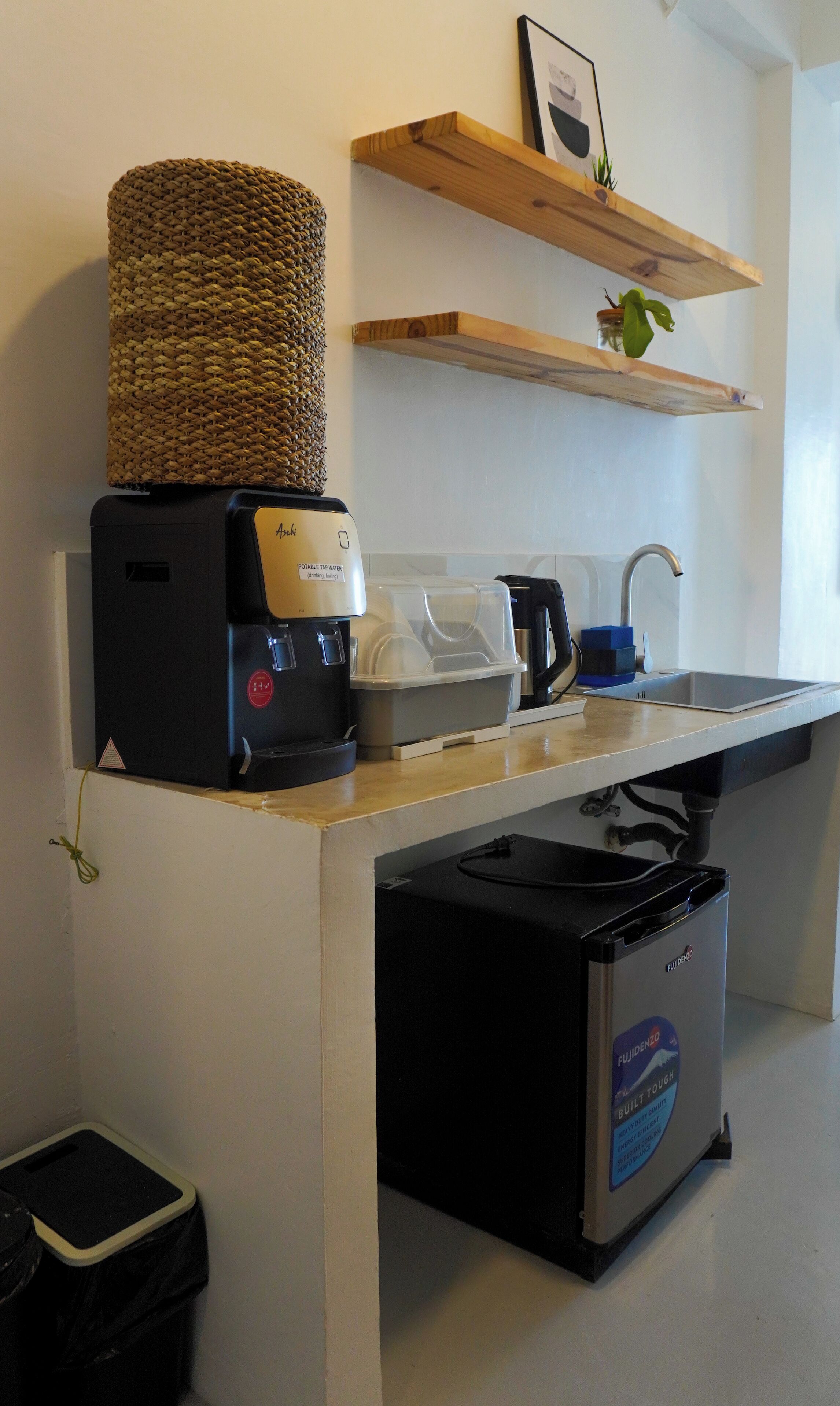 Angolo cottura con macchina del caffè, bollitore, lavandino e cestino.