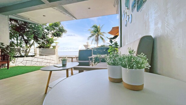 A modern outdoor seating area with a table and chairs, potted plants, and a view of the ocean. - Happy Island Inn (Virac)