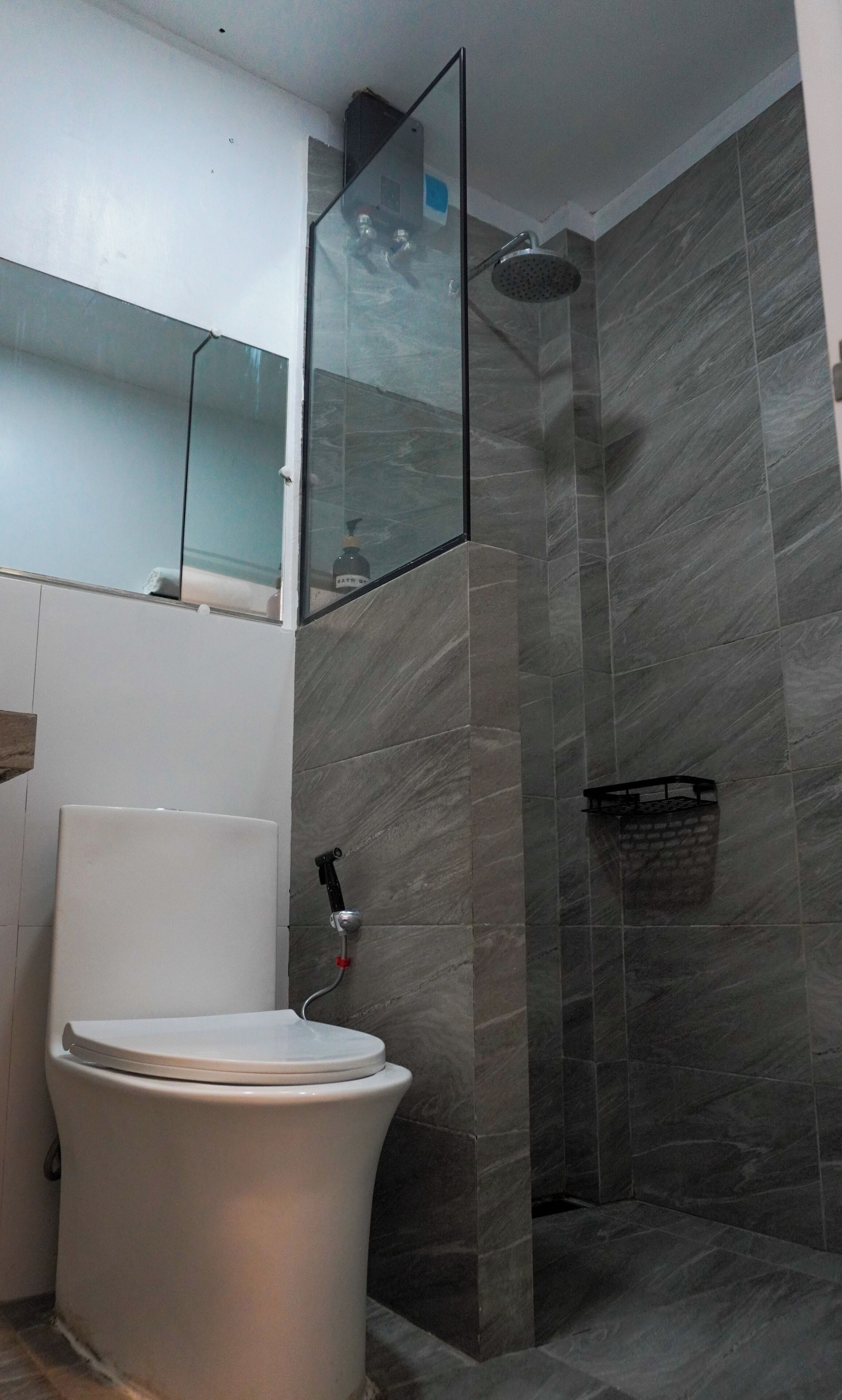A bathroom with a toilet, a glass shower enclosure, and a tiled wall.