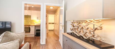 A modern kitchen with wooden cabinets, a built-in oven, and a dining area with a wicker chair.