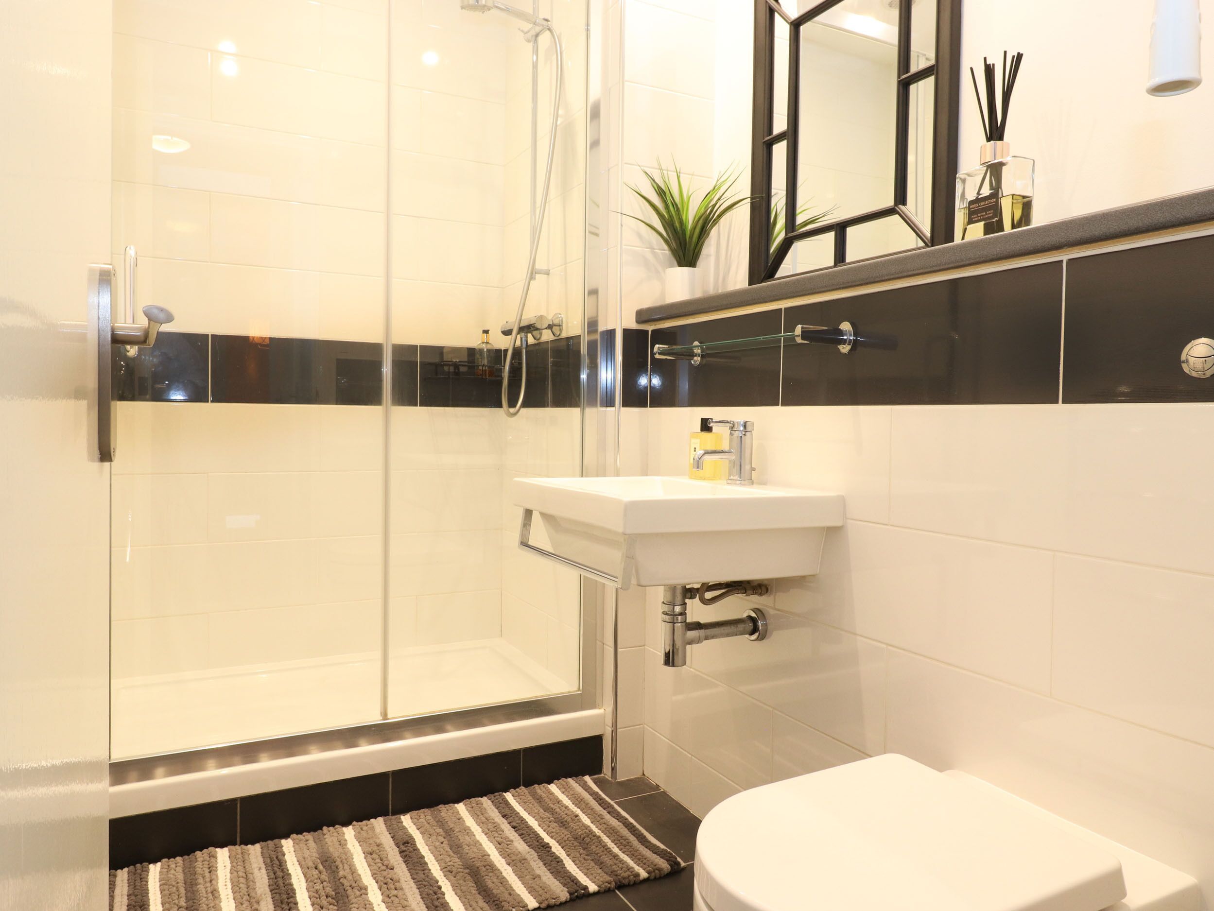Ein modernes Badezimmer mit einer Glaskabine zur Dusche, einem weißen Waschbecken und einer Toilette.