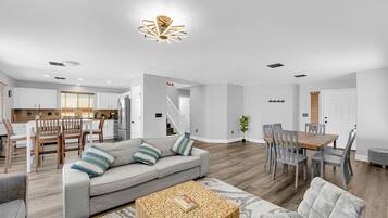 Amplia sala de estar con un sofá gris, una mesa de centro de madera y una mesa de comedor con sillas.