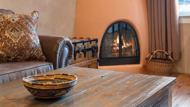 Un salon chaleureux avec une cheminée, un canapé, une table basse et un panier en osier.
