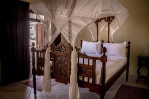 A four-poster bed with a canopy, wooden headboard, and a nightstand.
