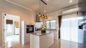 A modern kitchen with a central island, white cabinetry, and pendant lighting. - New 2 Bedroom Pool Villa C882 (Hua Hin)