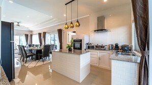 A modern kitchen with white subway tiles, a central island, and pendant lighting. - New 2 Bedroom Pool Villa C882 (Hua Hin)