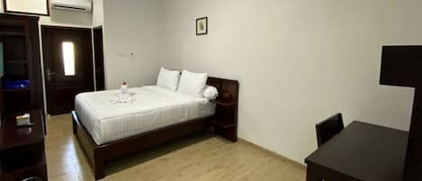 Un dormitorio con cama, mesita de noche y escritorio.