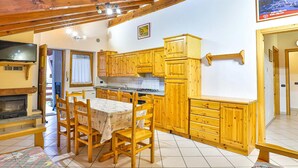 A cozy kitchen with wooden cabinets, a dining table, and a fireplace. - Apartment La Gran Becca - ID 530 (Antey-Saint-Andre)