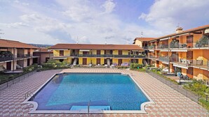 A hotel with a swimming pool, multiple balconies, and a courtyard. - Appartamento Chiaretto (Moniga del Garda)