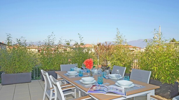 A dining table set outdoors with chairs, a book, and a vase with flowers. - Appartamento Chiaretto (Moniga del Garda)