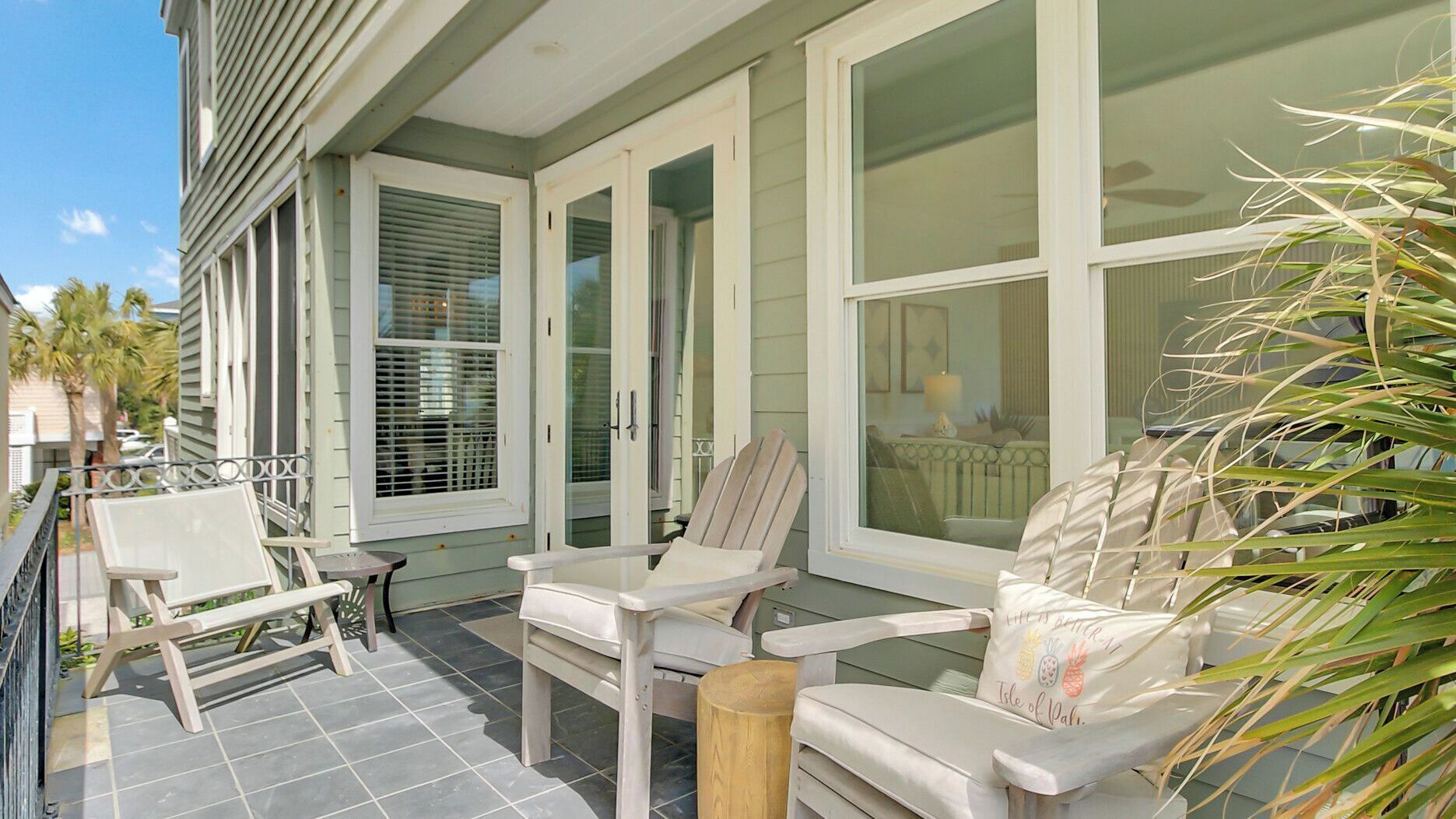 A covered patio with a seating area, large windows, and a view of the interior.