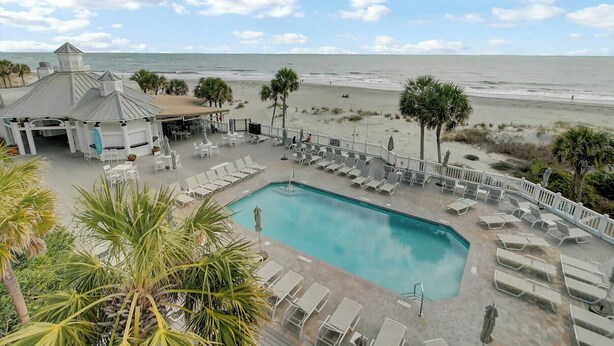 A pool area with lounge chairs and a view of the beach. - 109 Grand Pavilion by Avantstay Beachfront Views (Isle of Palms)