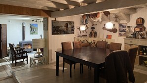 Ruokailutila, jossa on suuri puinen pöytä ja tuolit, takka sekä erilaisia seinäkoristeita.
