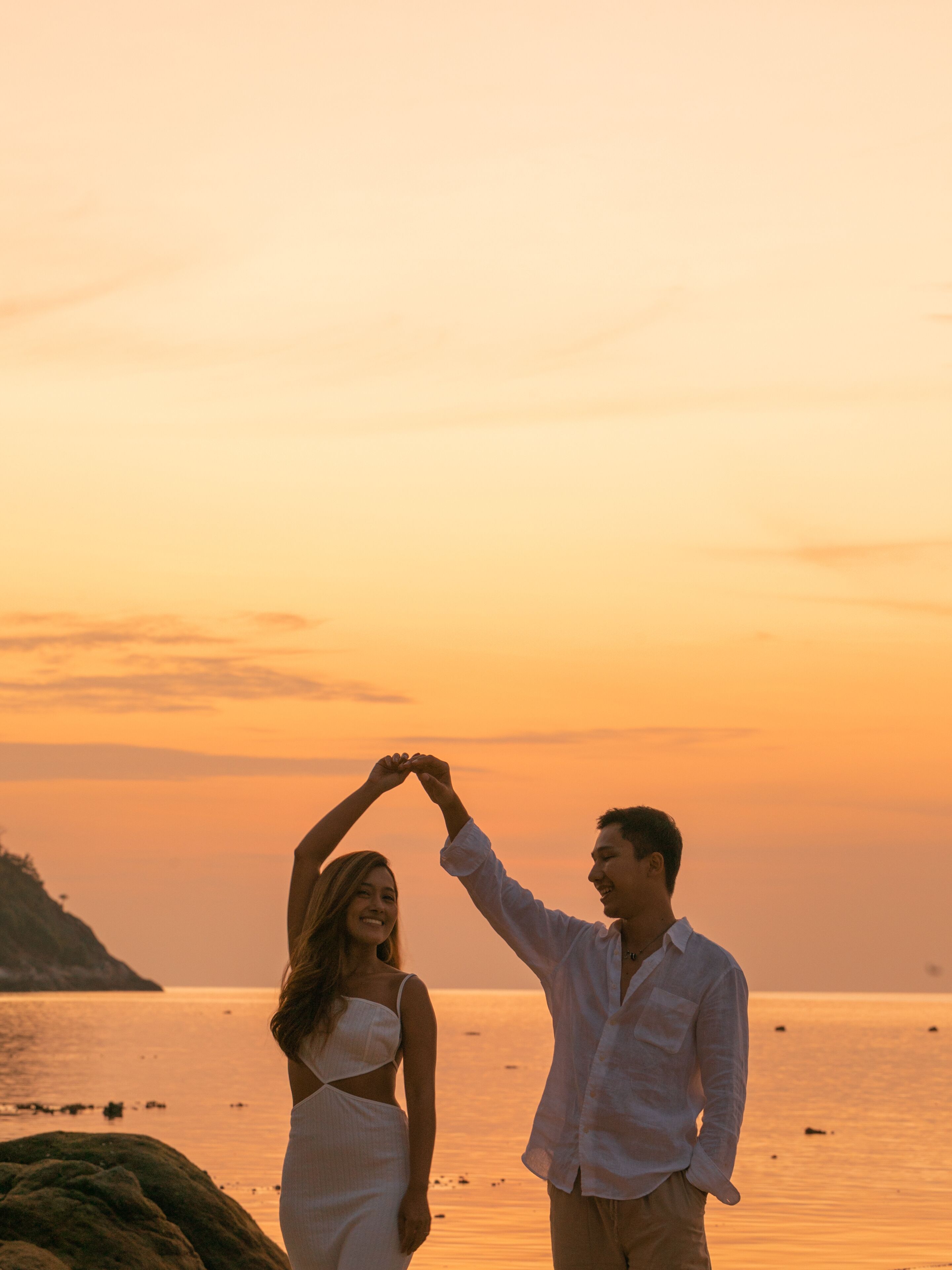 Een koppel houdt hand in hand op het strand bij zonsondergang.